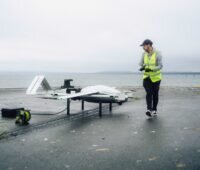 Ein Mann in gelber Weste mit einer der Transportdrohnen, die RWE zur Wartung von Offshore-Windparks nutzt.