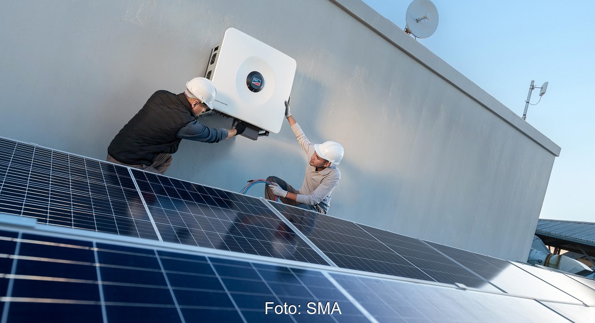Im Bild zwei Männer, die einen Sunny Tripower X 60 Photovoltaik-Wechselrichter von SMA an eine Außenwand schrauben.