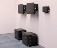Schwarze Geräte an rosa Wand: Die Clusterbox von Solarwatt kann mehrere Batteriespeicher zu einem Gesamtsystem kombinieren.