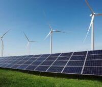 Photovoltaik-Module vor Windenergieanlagen, Projektentwickler Baywa re hat die Planungen für die Restrukturierung aktualisiert.