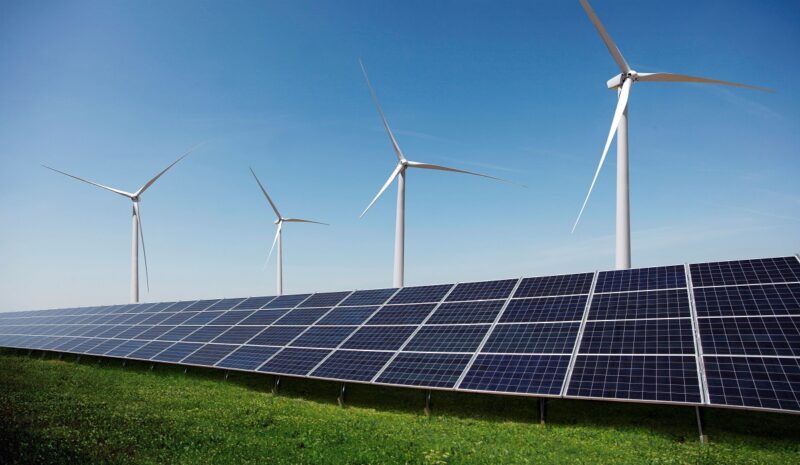 Photovoltaik-Module vor Windenergieanlagen, Projektentwickler Baywa re hat die Planungen für die Restrukturierung aktualisiert.