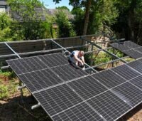 Ein Mann schraubt an Garten-PV, einer Garten-Solaranlage in Form einer Mini-Photovoltaik-Freiflächenanlage für den privaten Garten.