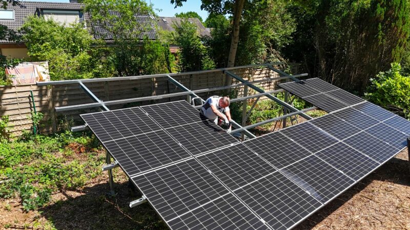 Ein Mann schraubt an Garten-PV, einer Garten-Solaranlage in Form einer Mini-Photovoltaik-Freiflächenanlage für den privaten Garten.