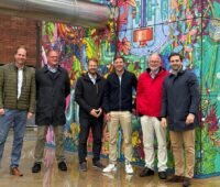 Vertreter von Enercity Contracting und Stadt.Energie.Speicher vor einem bunt bemalten Klimaturm, der die Integration von Großwärmepumpen in dicht bebauten Quartieren erleichtern soll.
