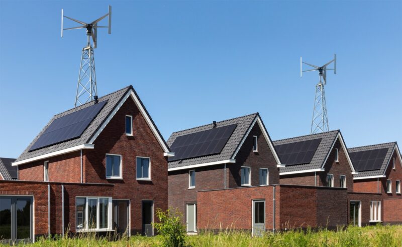 Im Bild Häuser mit Photovoltaik und vertikalen Kleinwindkraft-Anlagen.