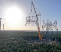 Ein Kran setzt eine Stahlkonstruktion auf einen Turm, die weltweit höchste Windenergieanlage entsteht in Brandenburg.
