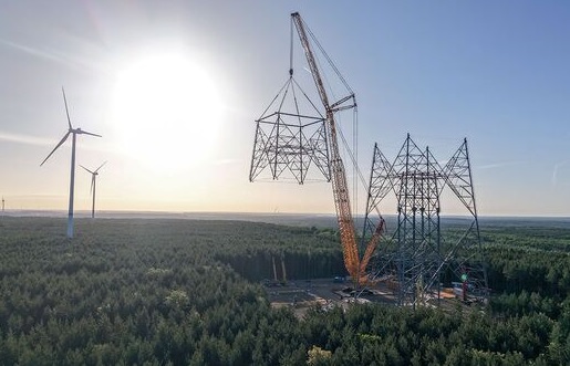 Ein Kran setzt eine Stahlkonstruktion auf einen Turm, die weltweit höchste Windenergieanlage entsteht in Brandenburg.