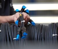 Hände halten einen werkseitig vorkonfektionierten Gleichstrom-Kabelbaum für die Photovoltaik-DC-Verkabelung.