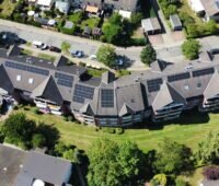 Ein Luftbild der Häuserzeile der Goslarer Wohnstättengesellschaft mit Photovoltaik-Anlagen für die Gemeinschaftliche Gebäudeversorgung.