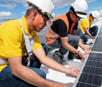 Arbeiter verlegen Solarmodule auf dem Dach, die Zukunft der Photovoltaik-Förderung in Österreich ist ungewiss.