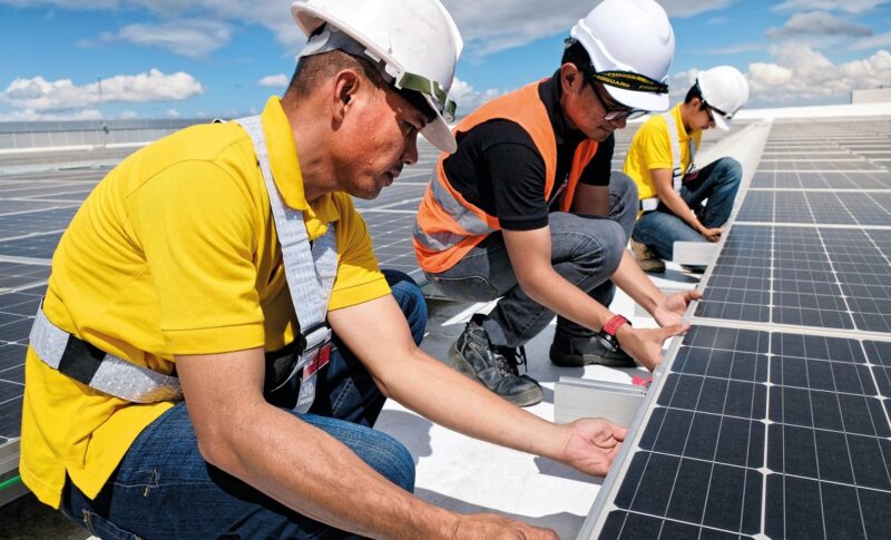 Arbeiter verlegen Solarmodule auf dem Dach, die Zukunft der Photovoltaik-Förderung in Österreich ist ungewiss.