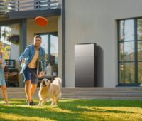 Eine Familie im Garten, an der Hauswand ein Photovoltaik-Batteriespeicher Ecoflow Ocean 2.