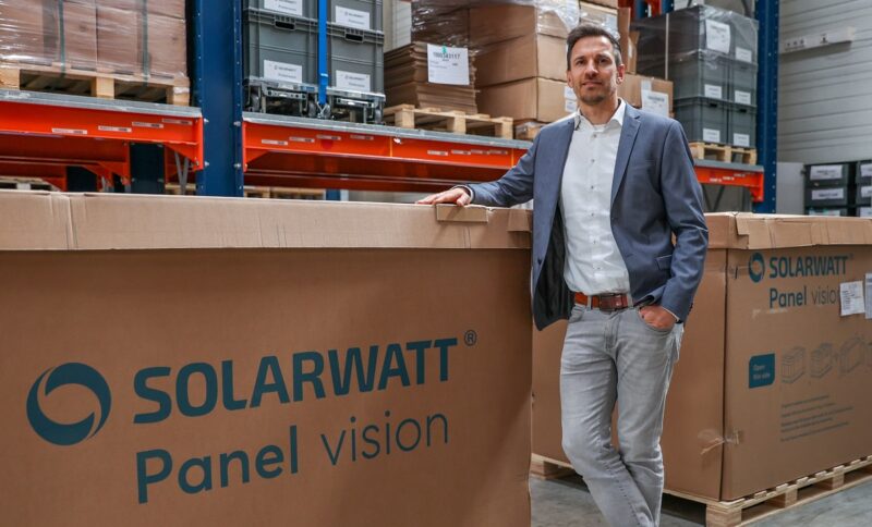 Im Bild Solarwatt-Produkt-Manager Gregor Kuschmann, der neben einem Karton mit der Aufschrift Panel Vision steht, das Unternehmen bietet leistungsstärkere TOPCon-Solarmodule an.
