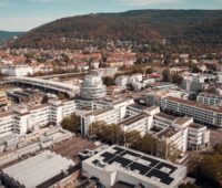 Luftbild von Heidelberg, im Vordergrund die Photovoltaik-Anlage des Heidelberger Bürogebäudes für die gemeinschaftliche Gebäudeversorgung.