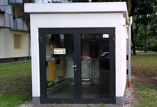 Ein Häuschen auf dem Gelände eines Wohnquartiers mit Komponenten für die gemeinschaftliche Gebäudeversorgung mit einem Quartierspeicher.