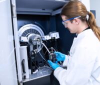 Ein Forscher mit weißem Kittel an einem Versuchsstand, die Pilotlinie des ZSW für Kathodenmaterialien für Batteriespeicher verfügt über mehr als 135 Anlagen und Geräte.