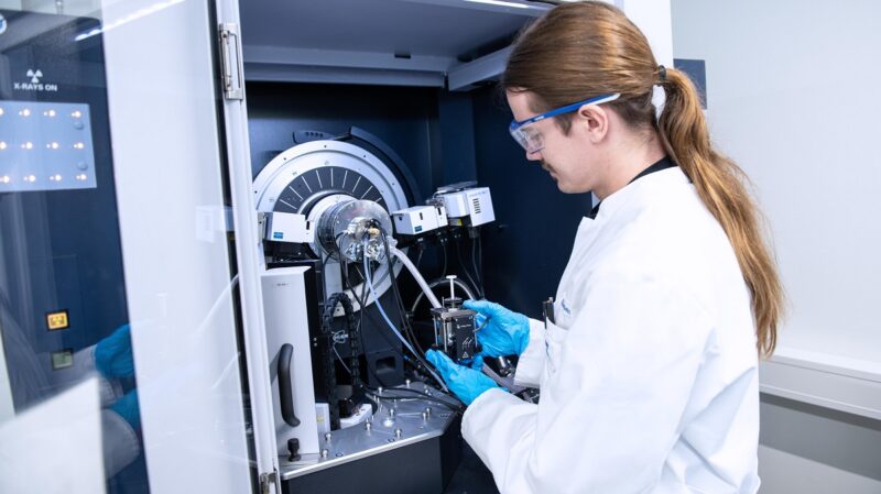 Ein Forscher mit weißem Kittel an einem Versuchsstand, die Pilotlinie des ZSW für Kathodenmaterialien für Batteriespeicher verfügt über mehr als 135 Anlagen und Geräte.