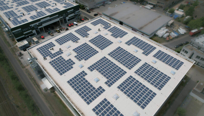Luftaufnahme einer Gewerbeimmobilie in Dreieich mit einer visualisierten Photovoltaikanlage aus zahlreichen Modulen auf dem Flachdach.