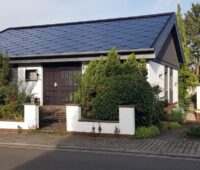 Einfamilienhaus von Martin Stoltenberg mit dunkelblauem, vollständig mit SunStyle-Solarziegeln gedecktem Satteldach, von der Straßenseite aufgneommen.