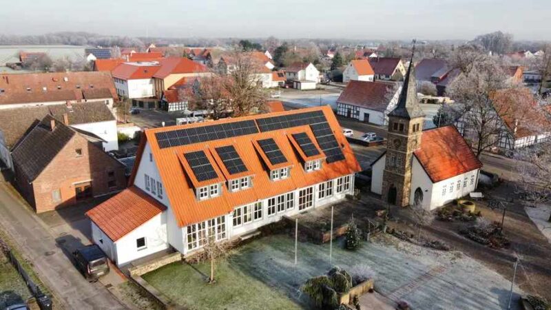 Luftbild einer Schule mit PV-Dach in einem Städtchen mit alter Kirche.