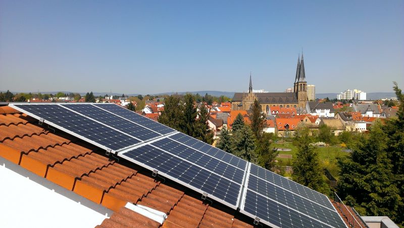 Schrägansicht eines PV-Schrägdachs. Im Hintergrund eine Stadt mit alter Kirche.