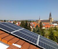 Schrägansicht eines PV-Schrägdachs. Im Hintergrund eine Stadt mit alter Kirche.