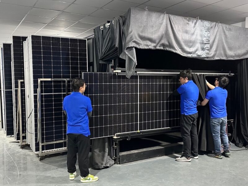 Mehrere Personen bewegen große Solarmodule in einer Halle.