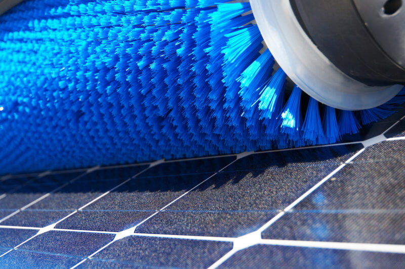 Blaue Bürste auf PV-Modul in Detailaufnahme - Symbol für Reinigung von PV-Freiflächenanlage und Wasseranschluss.