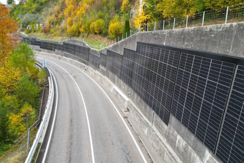Blick auf die Umgehungsstraße. An der Stützmauer auf der rechten Seite ist eine Photovoltaikanlage installiert.