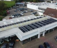 Luftaufnahme zeigt Autohaus mit PV-Anlagen auf dem Dach.