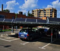 Autos auf einem mit PV-Modulen überdachten Parkplatz.