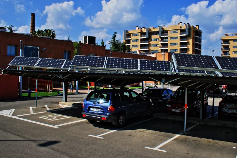 Autos auf einem mit PV-Modulen überdachten Parkplatz.