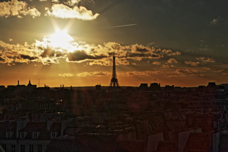 Paris mit Eifelturm vor teif stehender Sonne hinter Wolken