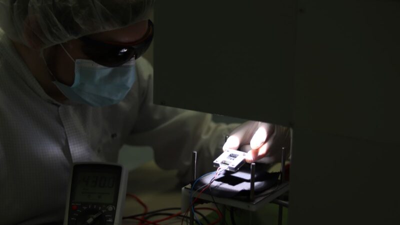 Ein Mensch legt eine Perowskit-Tandem-Solarzelle in einen Sonnensimulator, um den Wirkungsgrad zu vermessen.