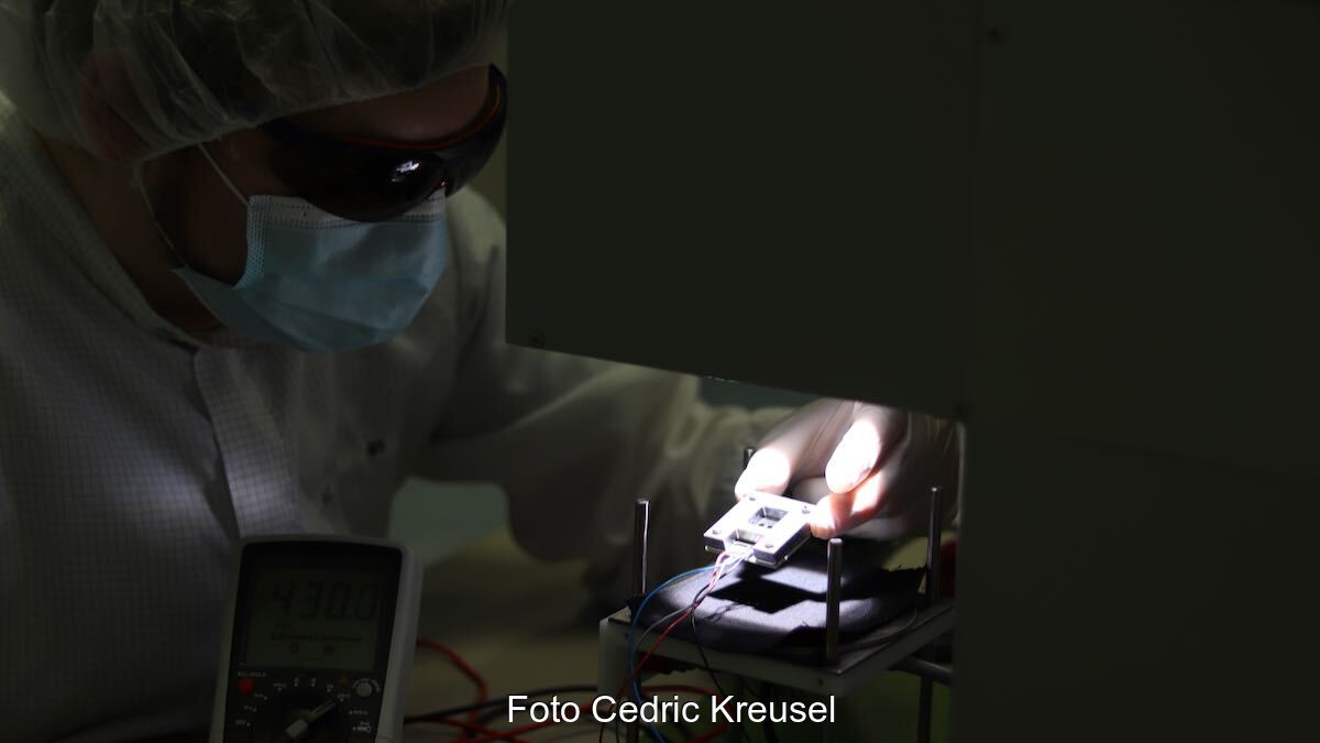 Ein Mensch legt eine Perowskit-Tandem-Solarzelle in einen Sonnensimulator, um den Wirkungsgrad zu vermessen.
