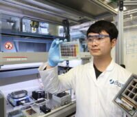Ein junger Forscher blickt im Labor auf eine Schablone mit verschiedenen, farbigen Materialien.