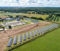 Luftbild einer Kläranlage mit Klärbecken und einer Reihe von Solarmodulen.