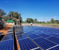 Photovoltaik-Anlage vor dunkelblauem Himmel auf rotem Boden, wenige Bäume - Solarstrom in Afrika.
