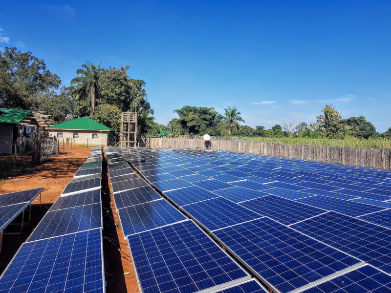 Photovoltaik-Anlage vor dunkelblauem Himmel auf rotem Boden, wenige Bäume - Solarstrom in Afrika.