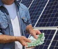 Im Bild ein Mensch mit Geldscheinen vor Solaranlage als Symbol für die Solar Direktinvest Gruppe.