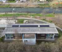 Luftaufnahme eines Hauses neben einem kleinen Fluss, Photovoltaik-Paneele auf dem Dach: Kita im Ahrtal