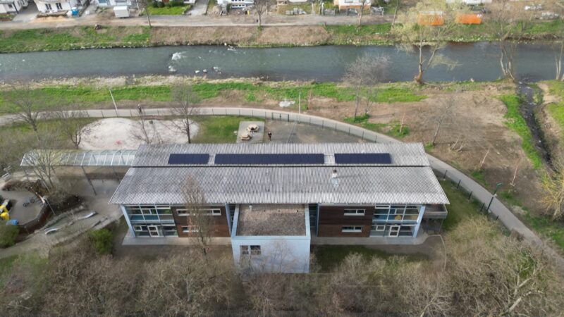Luftaufnahme eines Hauses neben einem kleinen Fluss, Photovoltaik-Paneele auf dem Dach: Kita im Ahrtal