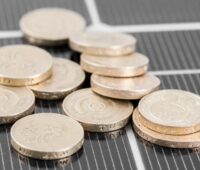 Münzen auf einem Photovoltaik-Modul als Symbol für Kosten von erneuerbaren Energien