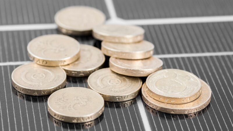 Münzen auf einem Photovoltaik-Modul als Symbol für Kosten von erneuerbaren Energien