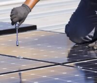 Montieren von Photovoltaik-Modulen auf einem Blechdach - mit der Photovoltaik-Pflicht in Baden-Württemberg wird es viel zu tun geben