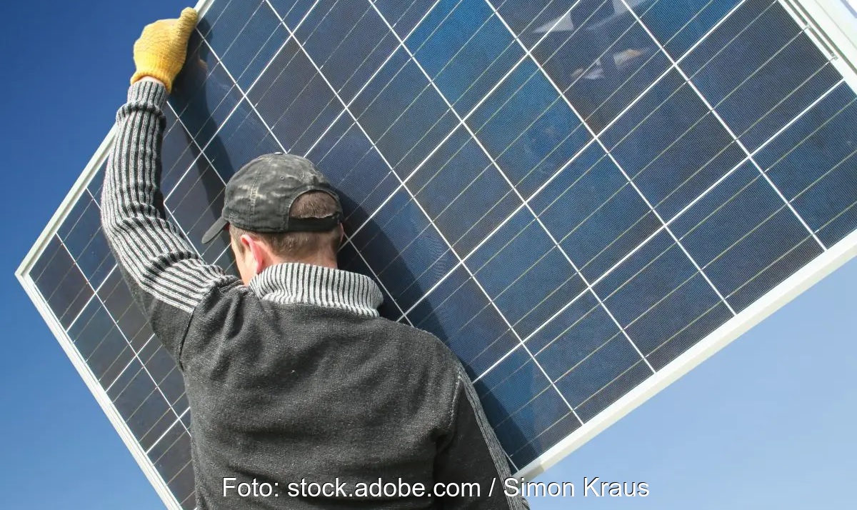 Ein Mann trägt ein PV-Modul, neues Faktenblatt „Repowering von Photovoltaik-Anlagen“.