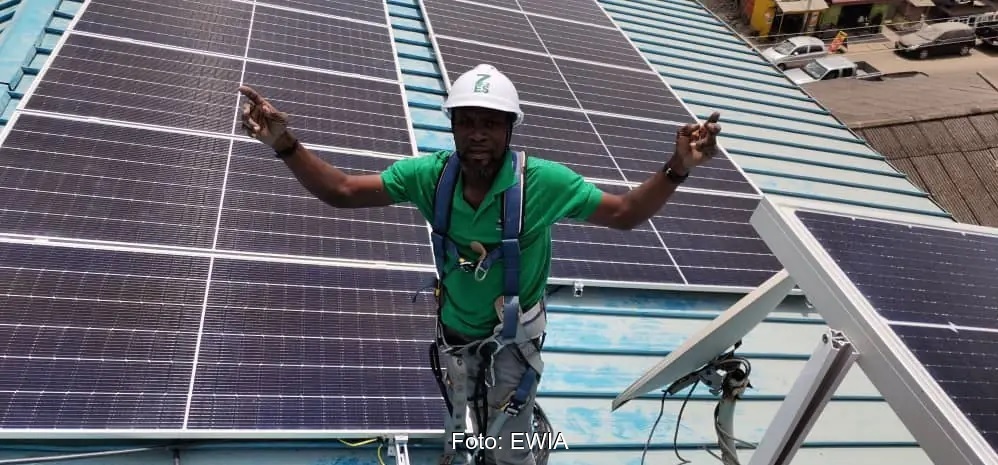 Im Bild ein Mann auf einem Dach mit Photovoltaik-Anlage in Afrika, EWIA übernimmt Sunergy.