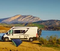 Zu sehen ist eine ausgeklappte Photovoltaik-Solartasche von Greenakku als Mini-PV-Anlage vor einem Camper in Berglandschaft.