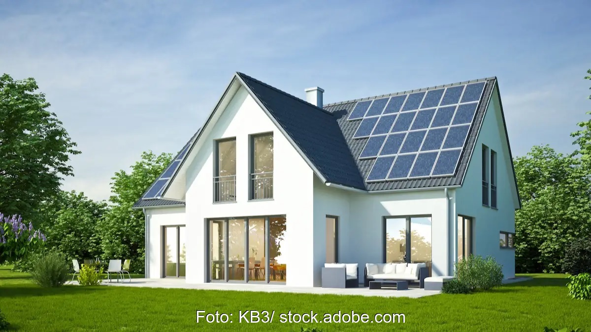 Im Bild ein weißes Einfamilienhaus mit Photovoltaik-Anlage auf dem Dach.