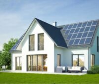Die Illustration zeigt ein modernes, weißes Einfamilienhaus im Grünen mit Rasen vor der Terrasse, links ein Sitzplatz, rechts Loungemöbeln, und Bäumen sowie Sträuchern dahinter, auf dem dunkelgrauen Dach eine PV-Anlage.
